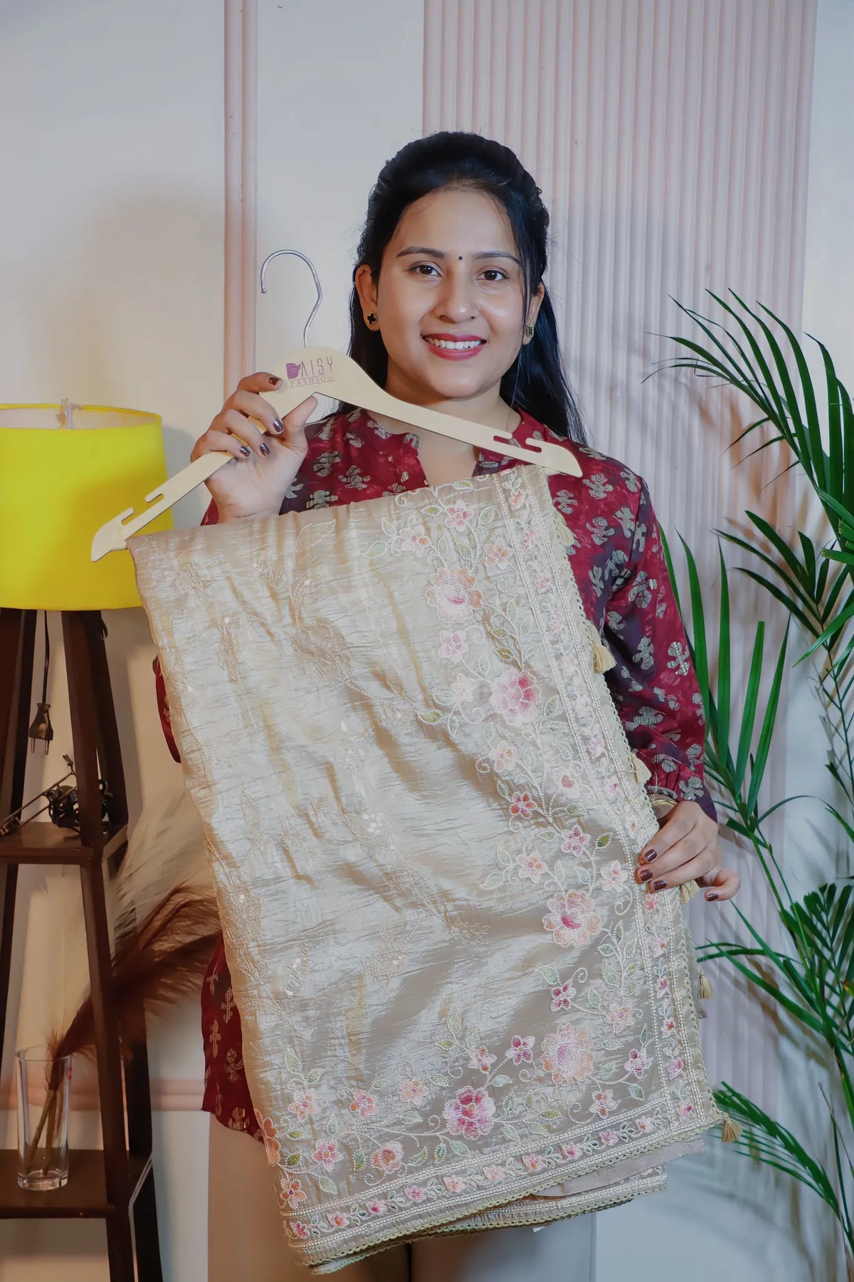 Beige silk saree, folded on a hanger to show the embroidery