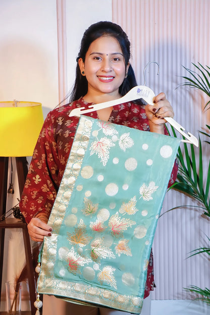 Pista green silk saree, folded on a hanger to show the woven motifs