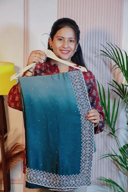 Teal blue satin saree, folded on a hanger with its embroidered border