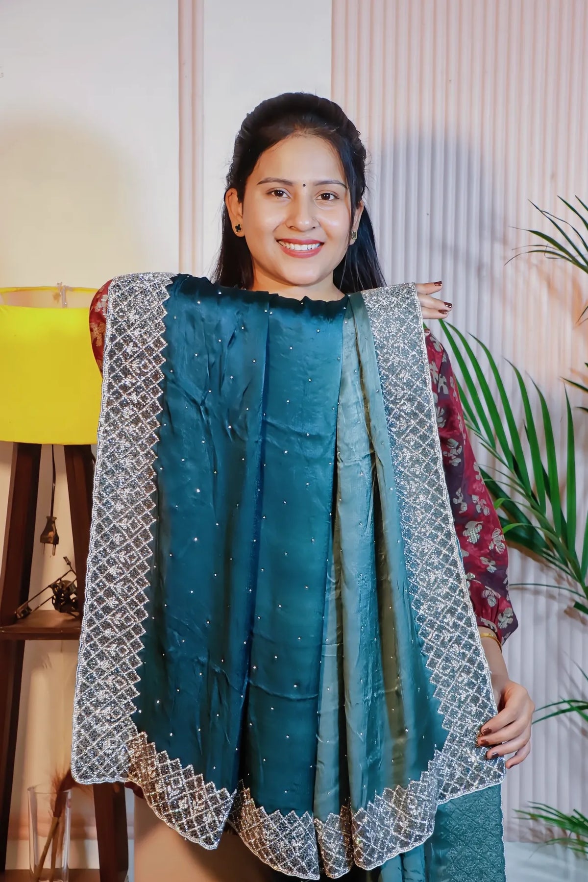 Teal blue satin saree, held open to show the embroidered border