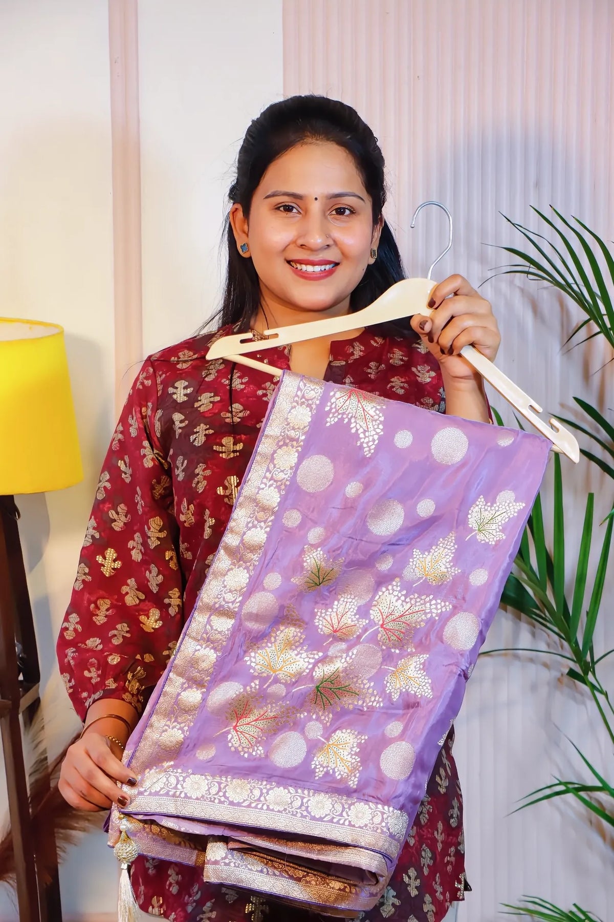 Purple silk saree, folded on a hanger to show the zari motifs
